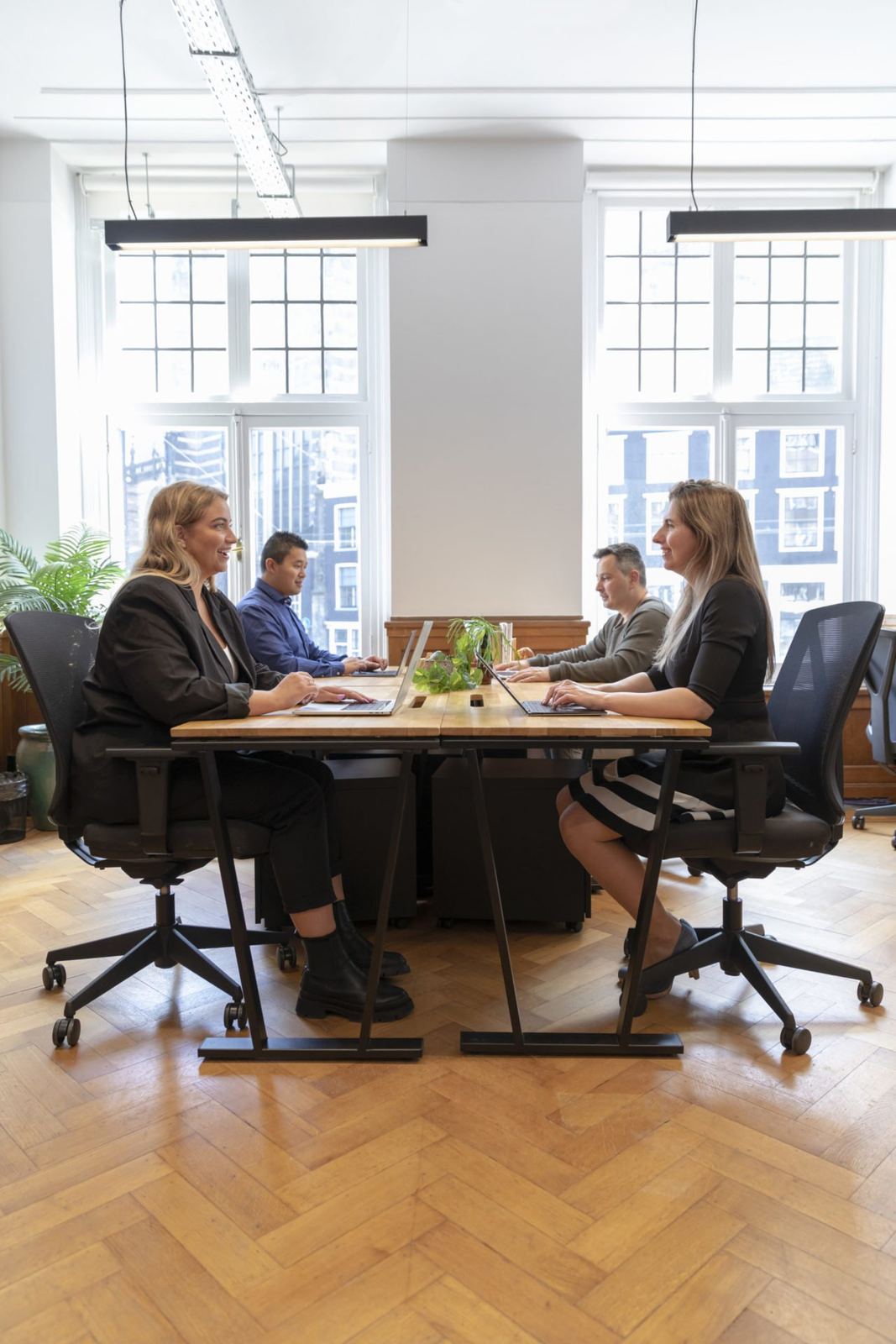 Vier collega's in overleg aan een tafel bij het raam